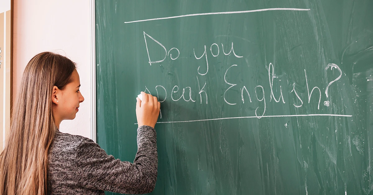 Nauczycielka angielskiego w technikum zapisuje na tablicy napis Do you speak English